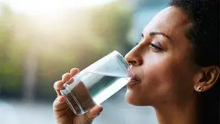 Женщина выпивает стакан воды. Женщина выпивает стакан воды.