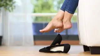 Женщина отдыхает, сидя на кровати, сняв обувь. Женщина отдыхает, сидя на кровати, сняв обувь.