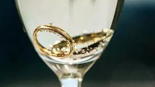 Изображение двух обручальных колец в бокале шампанского.
