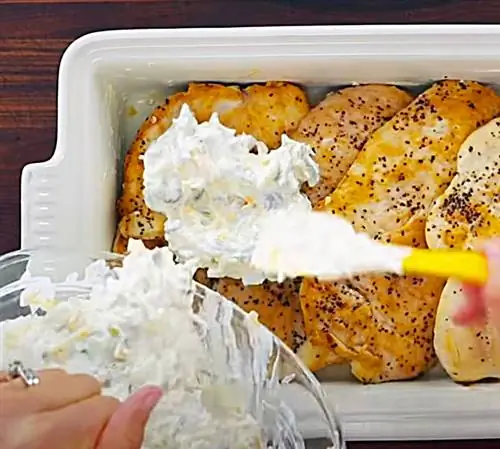 Покройте обжаренные куриные грудки сор-кремом и зеленым перцем чили для мексиканской запеканки