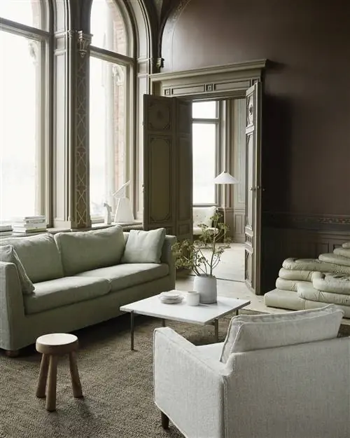 Старинная гостиная с бледно-зеленым чехлом на диван Bemz Ikea, современным белым журнальным столиком и белым креслом.