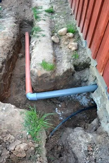 Траншея возле дома с водопроводными и канализационными трубами