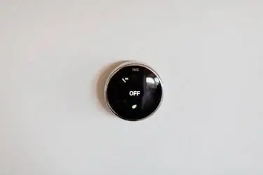 Термостат Nest на белой стене.