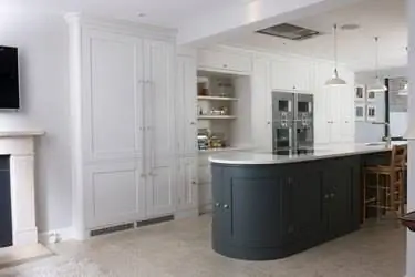 белая кухня с изогнутым зеленым кухонным островом