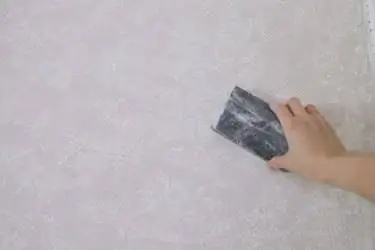 Шлифование высушенной римской глины на стене
