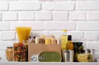 Набор сырых продуктов на полке кладовой, подготовленный к чрезвычайным ситуациям на фоне кирпичной стены Набор сырых продуктов на полке кладовой, подготовленный к чрезвычайным ситуациям на фоне кирпичной стены