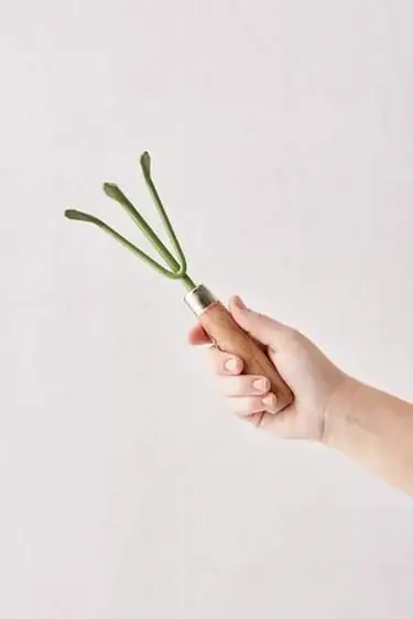 рука держит зеленые грабли