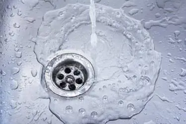 Слив воды на фоне раковины. Слив воды в умывальнике