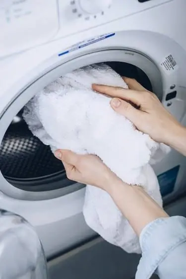 Рука достает белое полотенце из сушилки для белой одежды