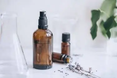 бутылки с эфирным маслом, веточки лаванды, стеклянный стакан и бутылка с распылителем, наполненная самодельным комнатным спреем