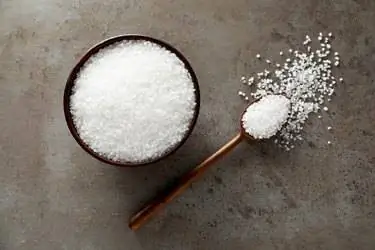 Чаша и ложка с натуральной морской солью на сером столе, плоская кладка Чаша и ложка с натуральной морской солью на сером столе, плоская кладка