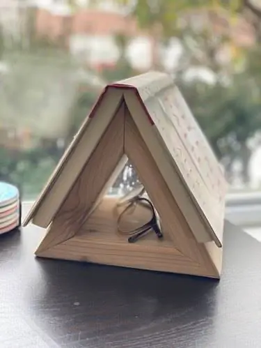 Треугольный книжный стенд с книгой и очками для чтения.