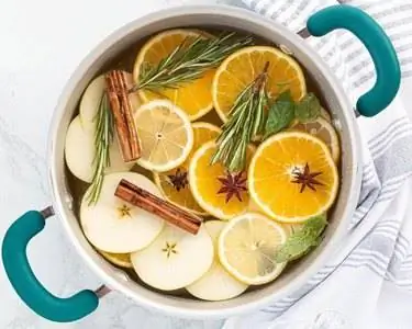 Дольки апельсина, дольки яблока, корица и розмарин в горшочке