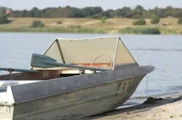 Старая алюминиевая рыбацкая лодка у озера или реки. Старая алюминиевая рыбацкая лодка у озера или реки.