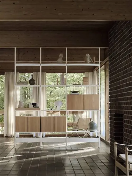 Стеллаж White String Furniture с дверью шкафа из светлого шпона в жилом помещении с окнами на заднем плане и кафельным полом. Стеллаж White String Furniture с дверью шкафа из светлого шпона в жилом помещении с окнами на заднем плане и кафельным полом.